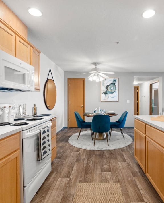 a kitchen with white appliances and a dining room with blue chairs