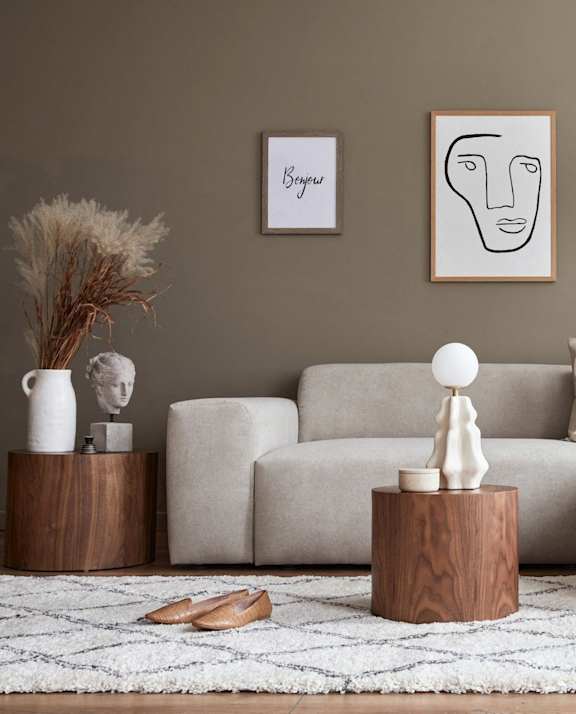 A living room with a grey sofa, a wooden table, and a white lamp.