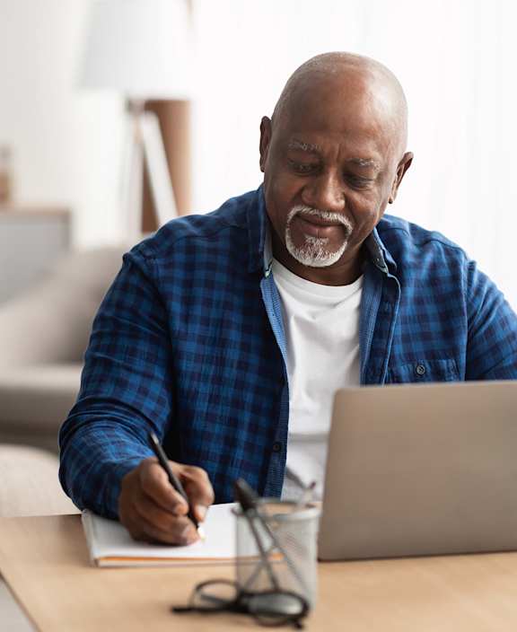 A man and a woman are sitting on a couch with a laptop.