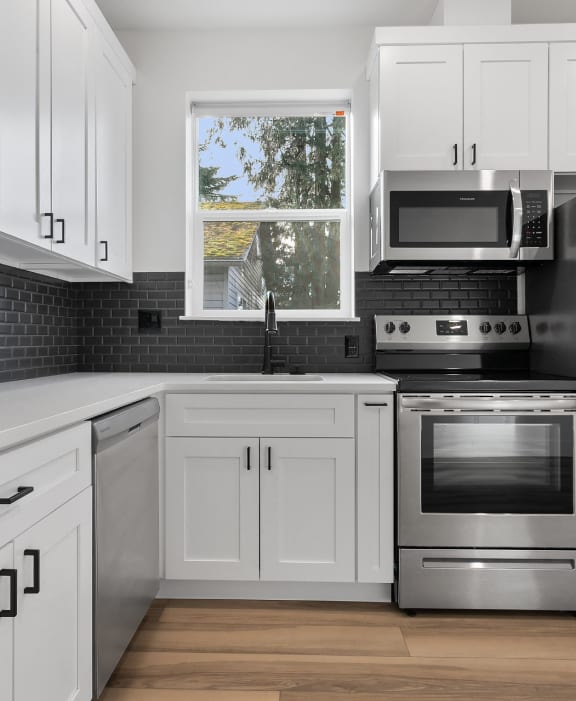 a kitchen with white cabinets and stainless steel appliances
