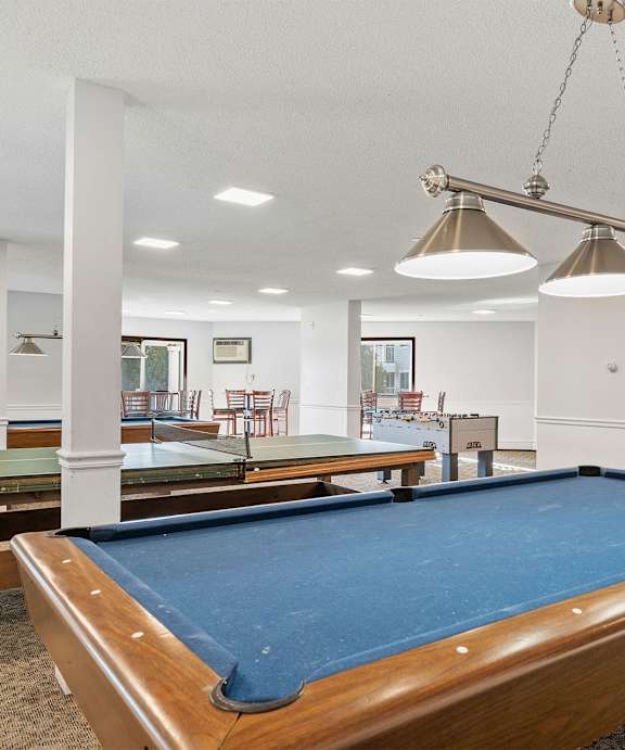 A pool table in a room with a light hanging from the ceiling.