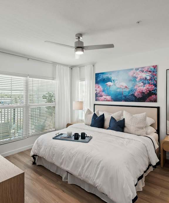 A bedroom with a large bed, a ceiling fan, and a painting on the wall. at Altis Twin Lakes Apartments, Kissimmee, FL 34744