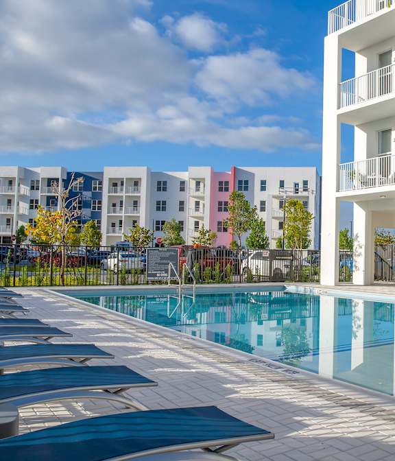 A swimming pool in front of a white building with a blue sky in the background.