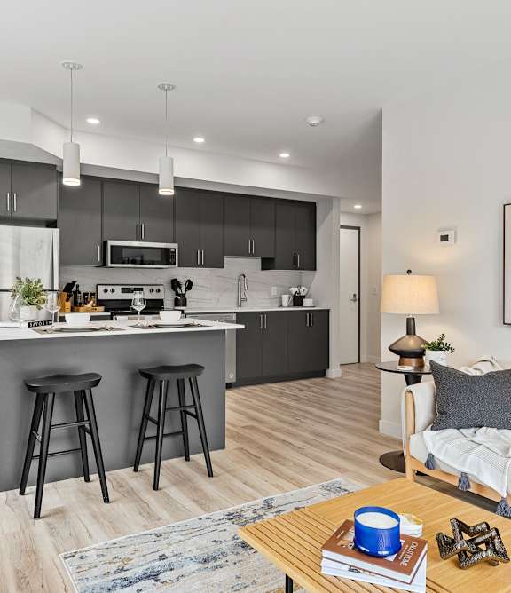 A modern kitchen with a glass table and black chairs.