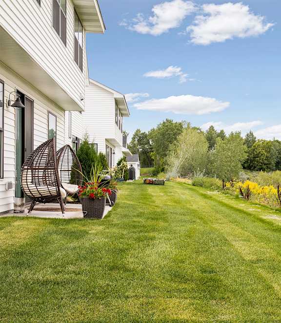 A white house with a lawn and a river in the background.