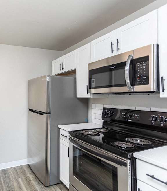 A kitchen with a stove, refrigerator, and microwave.