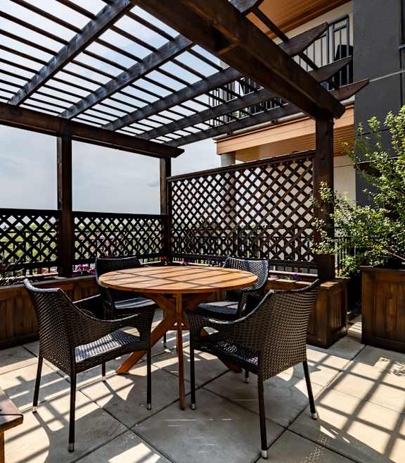 A patio with a table and chairs under a wooden roof.at Raymond Block, Edmonton, AB T6E 3R7