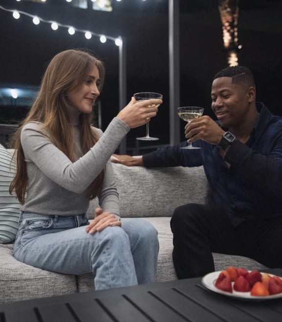 a man and a woman sitting on a couch with glasses of wine