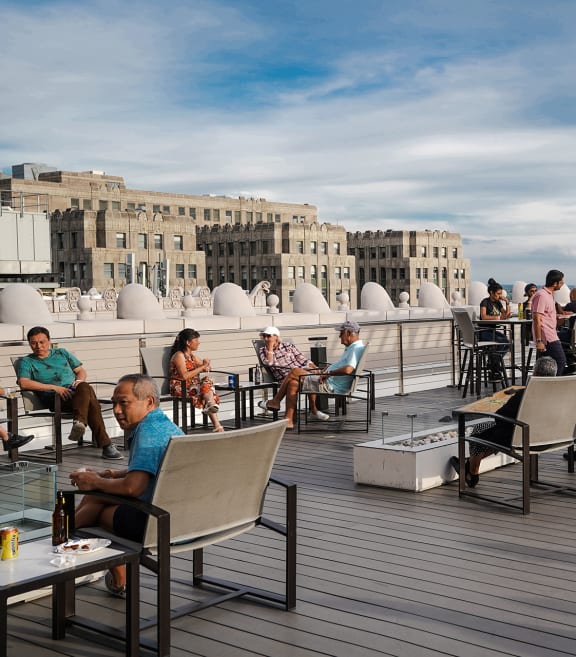 people sitting on chairs on a wooden deck with a blue sky in the background