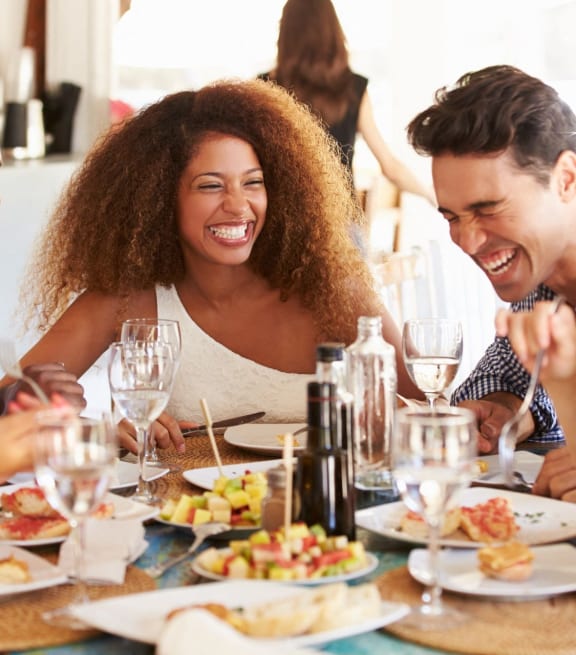 Group of Friends Smiling while Having Food and Drinks Together