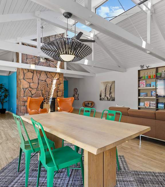 A room with a table and chairs in the foreground and a shelving unit in the background.
