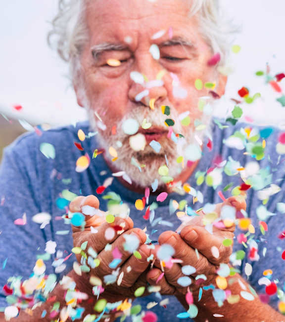 an older man with white hair and a blue shirt is covered in sprinkles