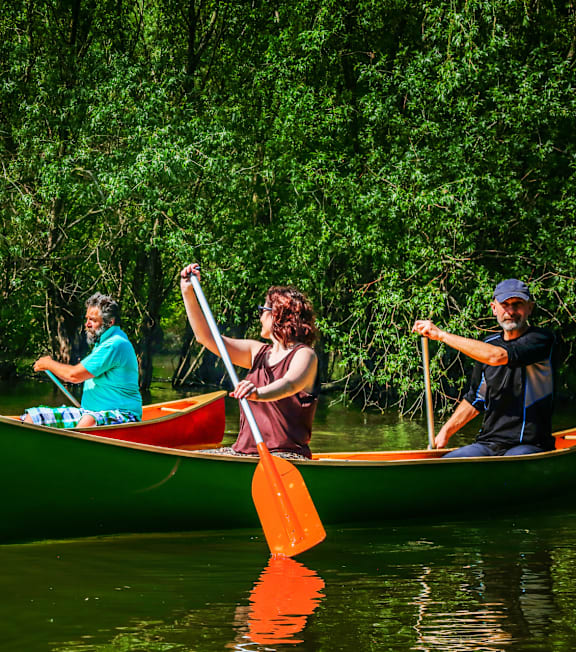 A woman in a kayak wearing sunglasses paddles through the water.
