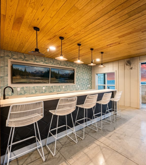 a bar with stools in a room with a large window