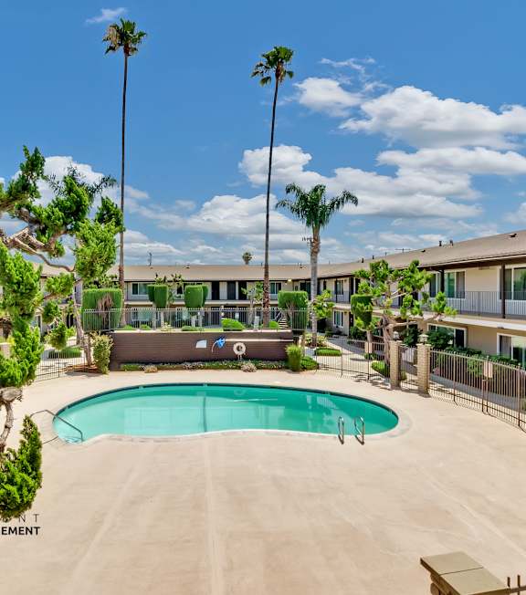 A pool with a hot tub and lounge chairs in front of a building.