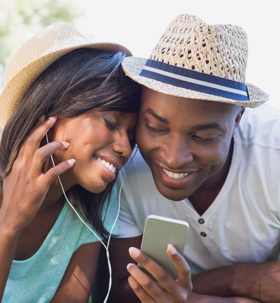 a man and woman laying on the grass looking at a cell phone
