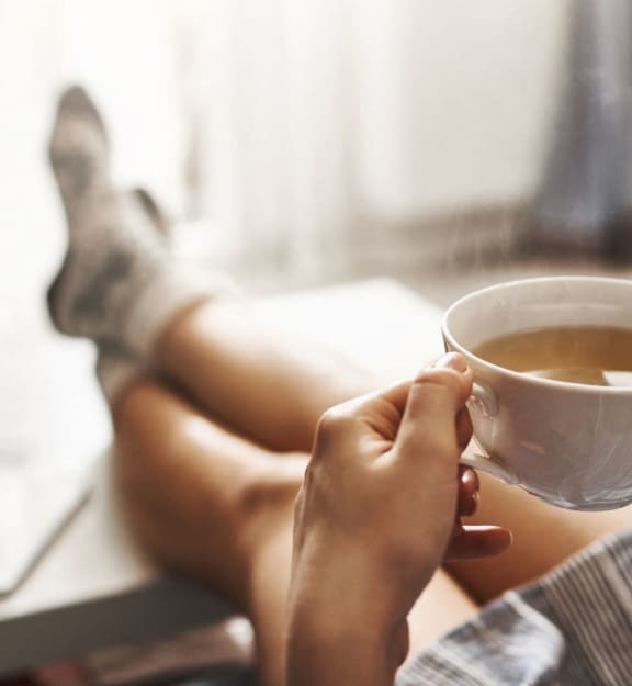 Woman Sitting Down and Holding Cup of Coffee