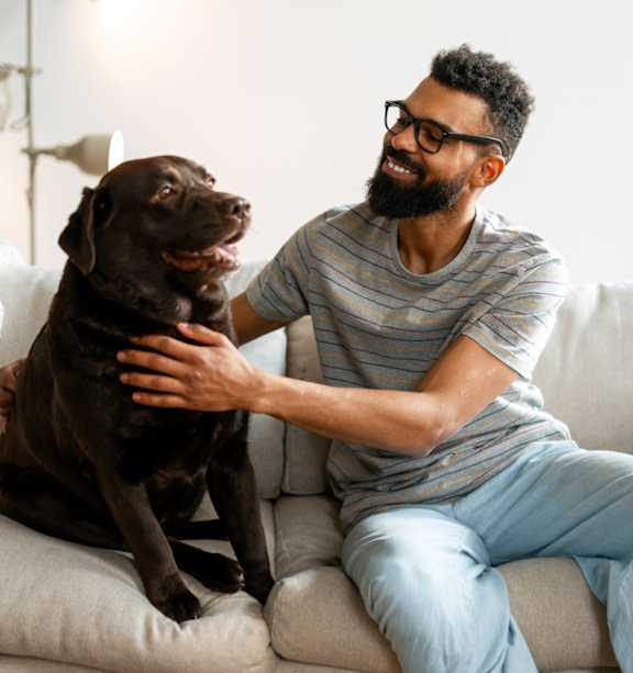 A man is sitting on a couch with a dog on his lap.