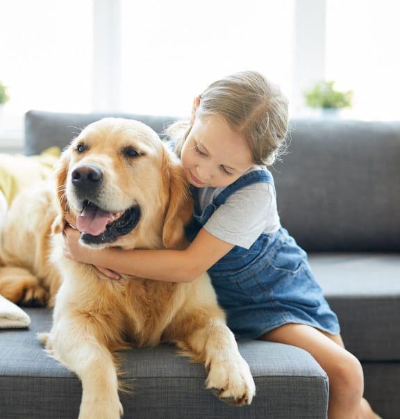 a little girl hugging a dog on a couch at Tucker Square, Stone Mountain, Georgia