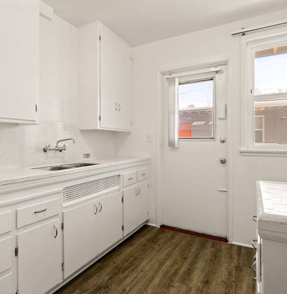 A kitchen with white cabinets and a window.