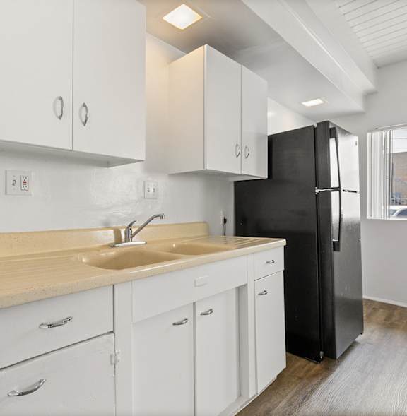 A modern kitchen with white cabinets and a black refrigerator.