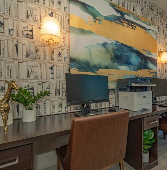 a desk with a computer and a painting on the wall