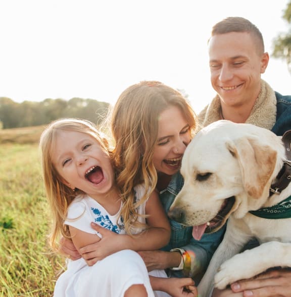 Family Smiling while Sitting with Dog in Grass