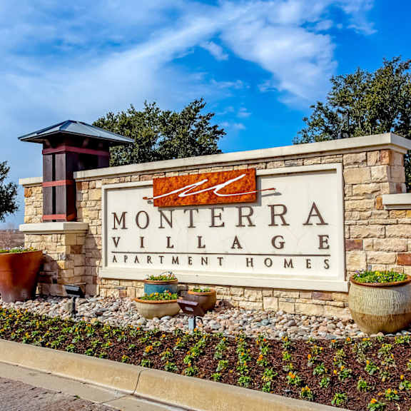 A sign for Monterra Village Apartment Homes is displayed in front of a building.