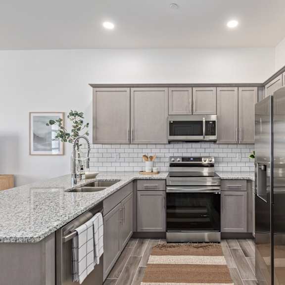 A modern kitchen with a granite countertop and stainless steel appliances.