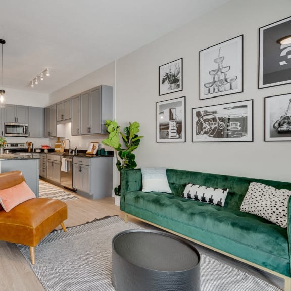 a living room with a green couch and a kitchen in the background