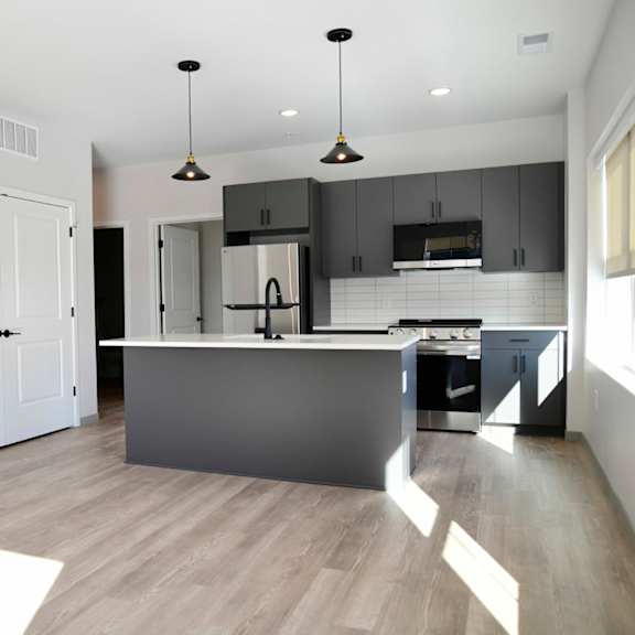 A modern kitchen with a wooden floor and white walls.