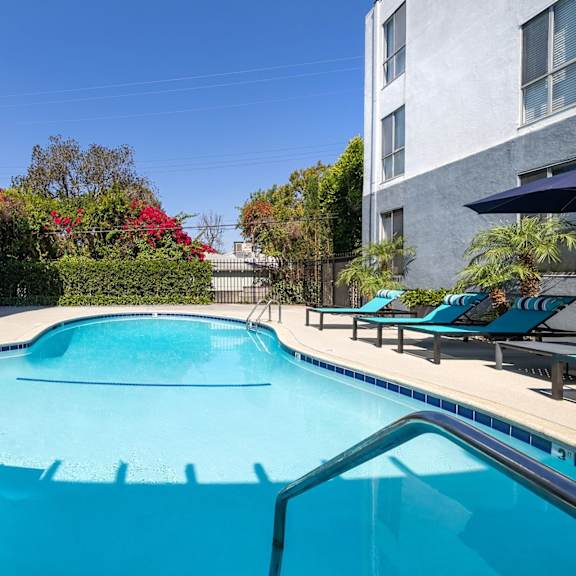 A swimming pool surrounded by lounge chairs and trees.