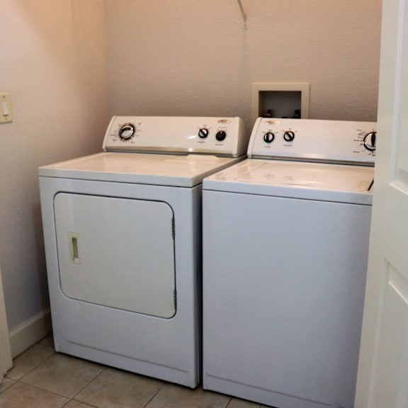 Two white front loading washing machines in a small laundry room.
