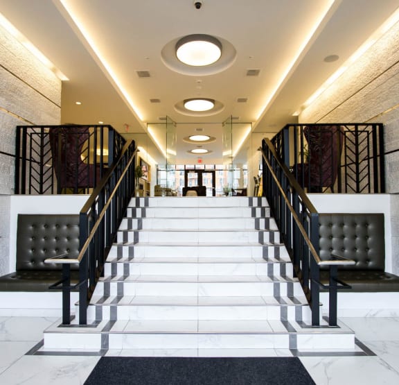 a long staircase with black metal railings and a white marble floor v