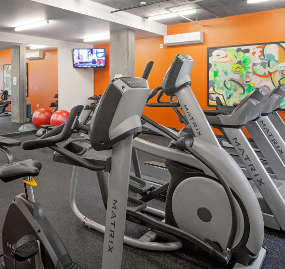 a room filled with lots of cardio equipment and a flat screen tv at The Parker, OR 97209