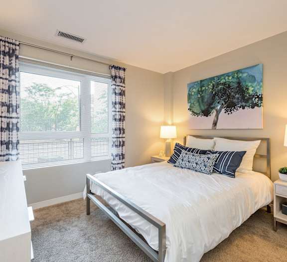 A bedroom with a large bed and a painting of a tree on the wall.