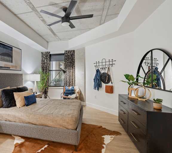 A bedroom with a bed, a dresser, and a ceiling fan.