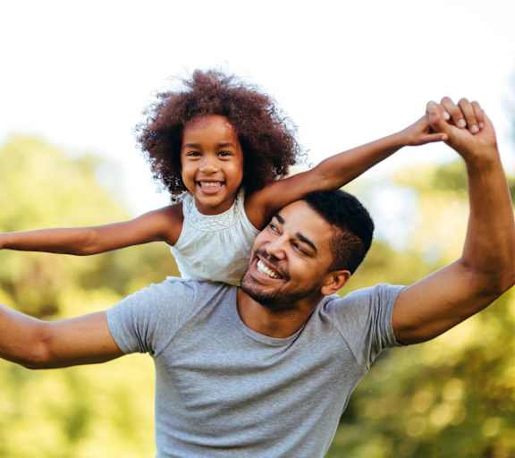 a father holding his daughter on his shoulders while playing in the park at Brightwaters Apartments, Little Rock, Arkansas