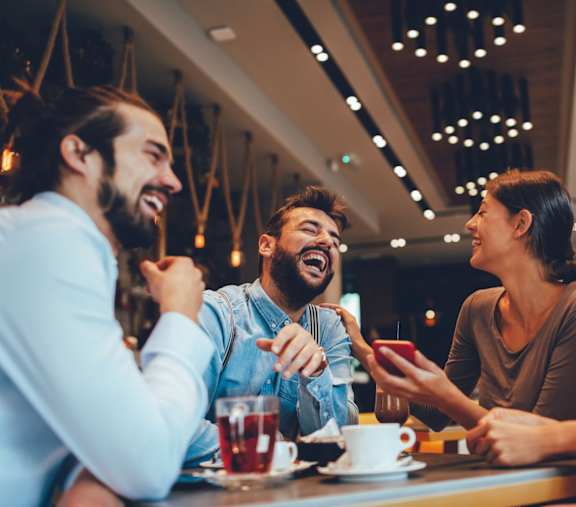 Four People are Sitting at a Table, Laughing and Enjoying at The Westerly at Union Depot Apartments, Bartlett, TN, 38134