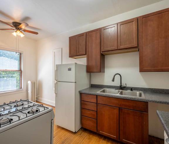 A kitchen with a stove, refrigerator, and cabinets.