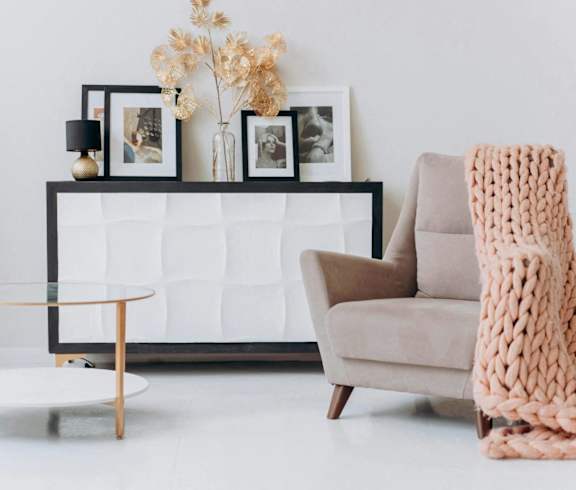 A cozy living room with a chair, a coffee table, and a knitted blanket.