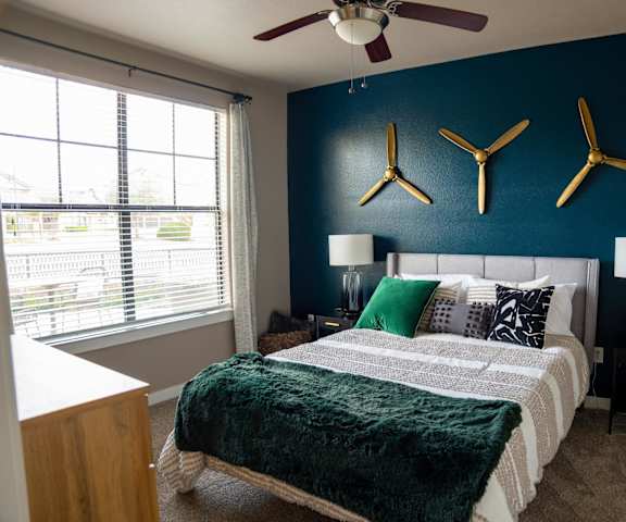 A bedroom with a bed, two lamps, and a ceiling fan.