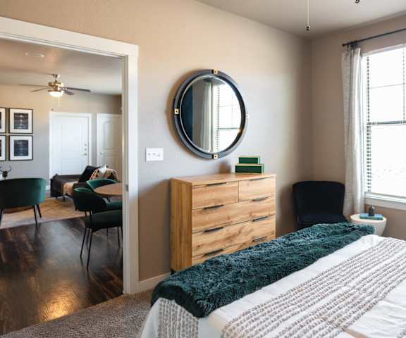 A bedroom with a bed, dresser, mirror, and chairs.