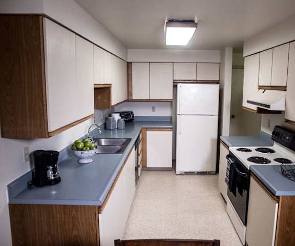 A kitchen with white cabinets and a stove and a refrigerator at Birchwood Homes Apartments.
