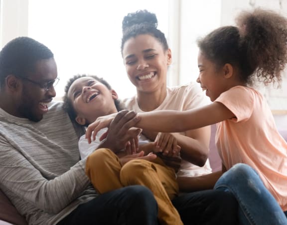 a family of four sitting on a couch laughing and holding their children at Glen Hollow, Decatur