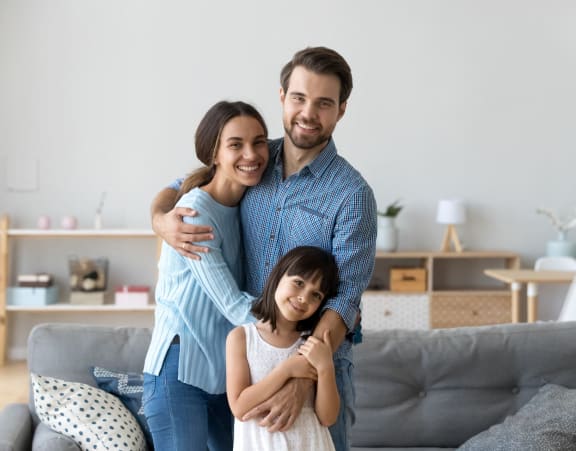 a man and woman hugging their daughter in a living room at Hidden Woods, Georgia, 30035