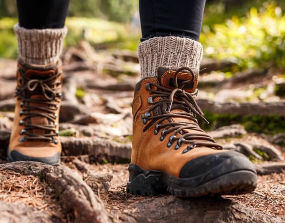 Close Up View of Person Wearing Hiking Boots Walking Through Forest