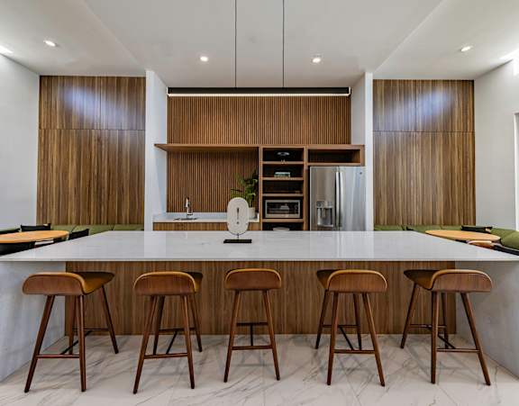 A modern kitchen with a long island and stools.