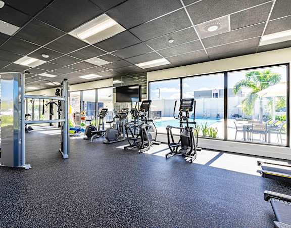 A gym with a variety of equipment including a treadmill, weights, and a bench.