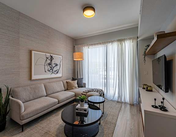 A living room with a grey couch, a coffee table, a television, and a painting on the wall.